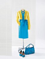 Yellow short jacket and turquoise silk dress on clothes stand