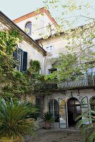bewachsenes Haus mit Fensterläden in Italien