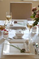 Table setting with white plate, wine glass and cutlery on table