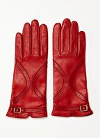 Red leather gloves with gold buckle on white background