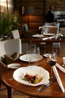 Venison in bowl and glass of wine on laid table at gourmet restaurant