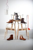 Various boots on stack of chairs against white wall
