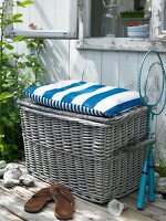 Wicker chest with hinged lid seat cover in blue white on wooden surface