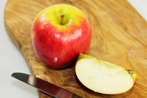 Close-up of whole and halved apple on wooden board