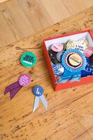 Close-up of rosette and badges in box, three rosettes besides it against wooden background