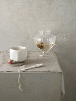 Stillleben mit Teeschale & Teeblume in einer Glasteekanne