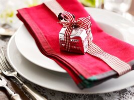 A place setting decorated with a red napkin and tiny present