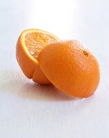 Close-up of two whole and two halved oranges on white background