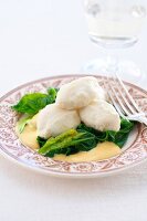 Pike dumplings with spinach and saffron sabayon on plate