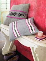 Scatter cushions with embroidered covers on wooden bench