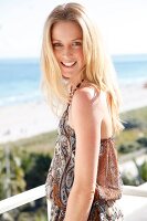 blonde Frau in Neckholder am Meer, Hintergrund Strand