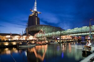 Night view of climate house at old port with moored boats in Bremerhaven, Bremen, Germany