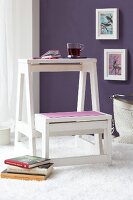 White step stool with cup and books on white fur carpet