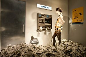 Mannequin standing in front of ATM machine symbolizing love of money in New York, USA