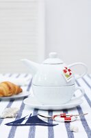 White teacup with attached pot on table