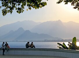 People sitting at promenade near sea and mountain range in Antalya, Turkey