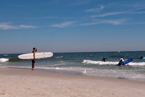 Man holding surfboard at Long Beach in New York, USA