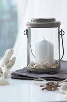 Lit candle in lantern decorated with shells