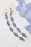 Close-up of long blue earrings made up of sapphires on white background