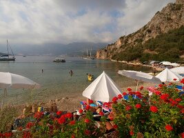 People relaxing under beach umbrellas on bay beach in summer