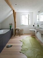 Modern bathroom with bathtub, sink, commode and green carpet on wooden floor