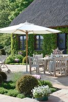Dining table under parasol against house with wild wine on wall