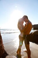 Couple romancing on beach with bright sunlight in background