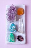 Overhead view of various gemstones used for therapy on purple background