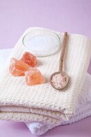 Block of salt crystals and powdered salt crystal in spoon on towels for sole therapy