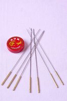 Close-up of acupuncture needles and balm on purple background