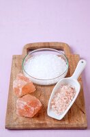 Block of salt crystals and powdered salt crystal in spoon on wooden board for sole therapy