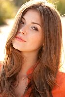 Portrait of beautiful woman with brown hair wearing orange top