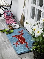 Doormat with frog motif of coconut and various shoes in front of house door