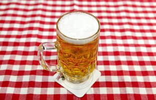 Glass of beer on red and white checked table cloth
