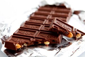 Close-up of chocolate with broken piece on silver paper