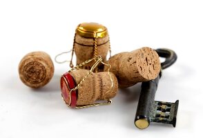 Several champagne corks with key shaped corkscrew on white background