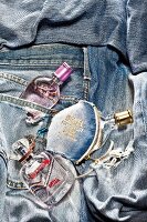 Close-up of three different perfume bottles on jeans