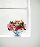 Bouquet of garden roses in vase on window sill