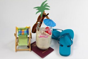 Sunglasses, flip flops, passport, deck chair, palm tree and jar full of sand