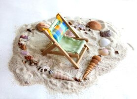 Deck chair in center of heart made of sea shells on sand