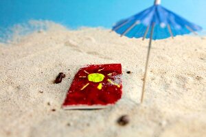 Handtuch und Sonnenschirm im Sand X 