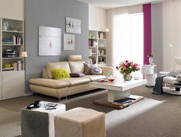 Living room with beige leather sofa, table, shelves and vase