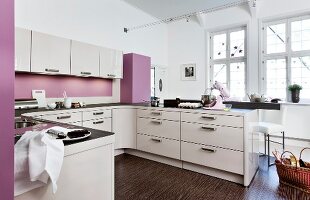 Küche, helle Fronten, gerundete Ecken und Kanten, rosa Wand