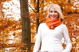 Portrait of blonde woman wearing white sweater and orange scarf, smiling