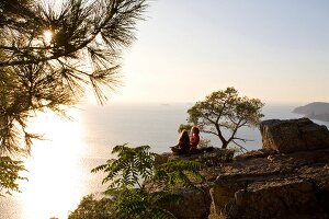Couple sitting on cliff in front of Marmara sea, Prince island, Istanbul, Turkey
