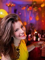 Portrait of happy woman in yellow top dancing while celebrating New Year's, smiling