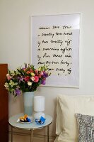 Table with flower vase and picture frame on wall