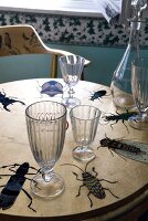 Glasses on table decorated with insects decoupage