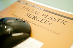 "Close up of brochure booklet of ""Facial Plastic Surgery"" and computer mouse"