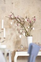 Easter eggs hanging on branches in white vase